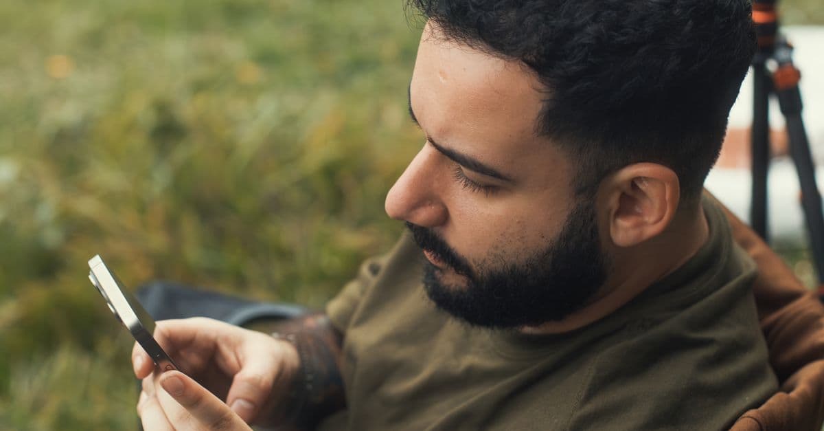 Jeune homme utilisant son smartphone en plein air grâce à sa vodafone esim pour rester connecté