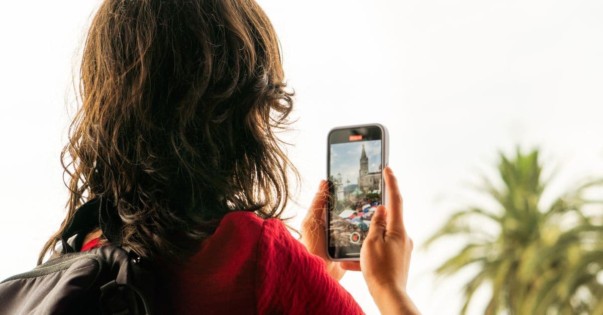 Mujer usando smartphone para conectarse a WiFi o eSIM de viaje en una ciudad mexicana.