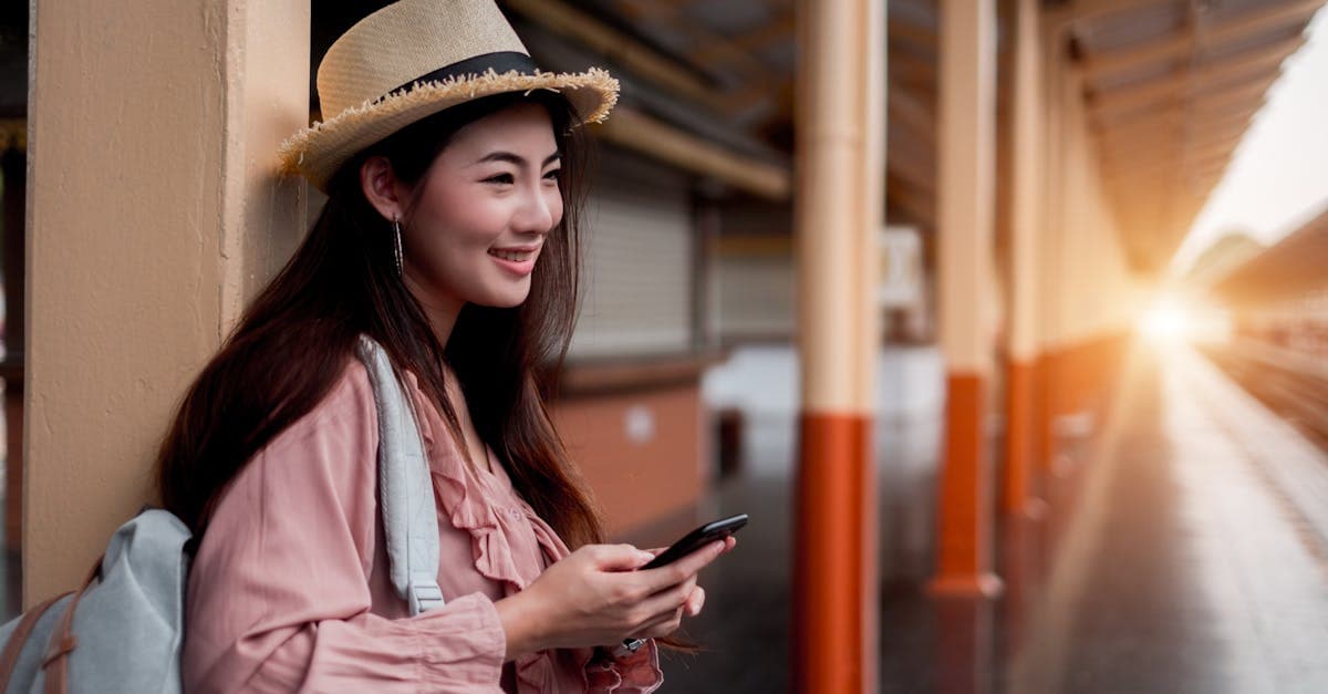 Traveller using a 5G-enabled travel sim card on her phone at a Singapore train station at sunrise.