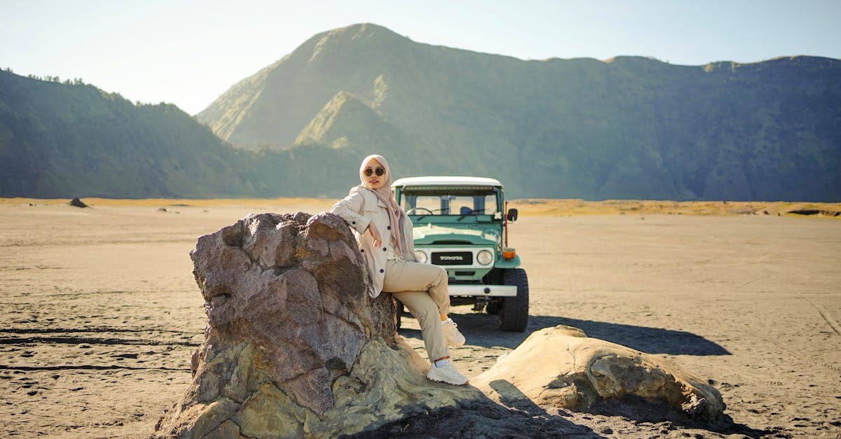 Perempuan berhijab berdiri di dekat Land Cruiser klasik dengan latar Gunung Bromo, Jawa Timur.