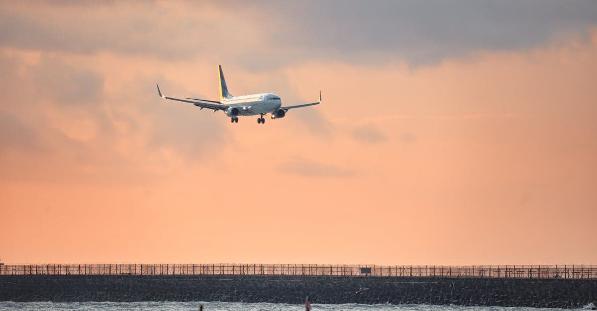 Plane descending over the ocean towards Bali Airport during perth to bali flights at sunset.