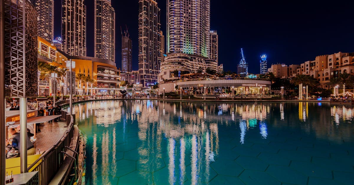 Nachtelijk uitzicht op de verlichte skyline van Dubai weerspiegeld in een vijver, twee uur vooruit op Nederland