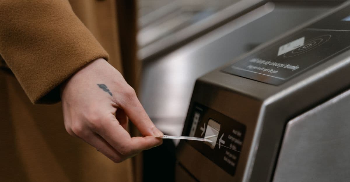A traveler taps a transit card against the reader on a station ticket gate.