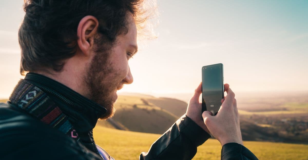 UK traveller photographing the Brighton coastline with a smartphone, staying connected abroad using a travel eSIM