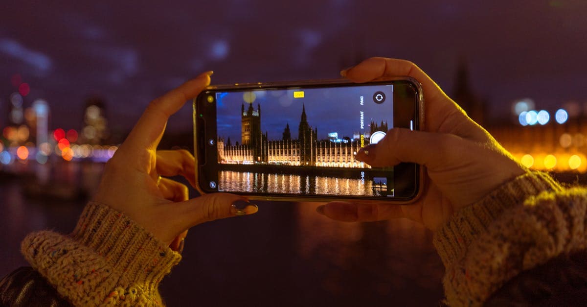 Traveller using a smartphone to photograph London's night skyline while staying connected abroad with mobile data