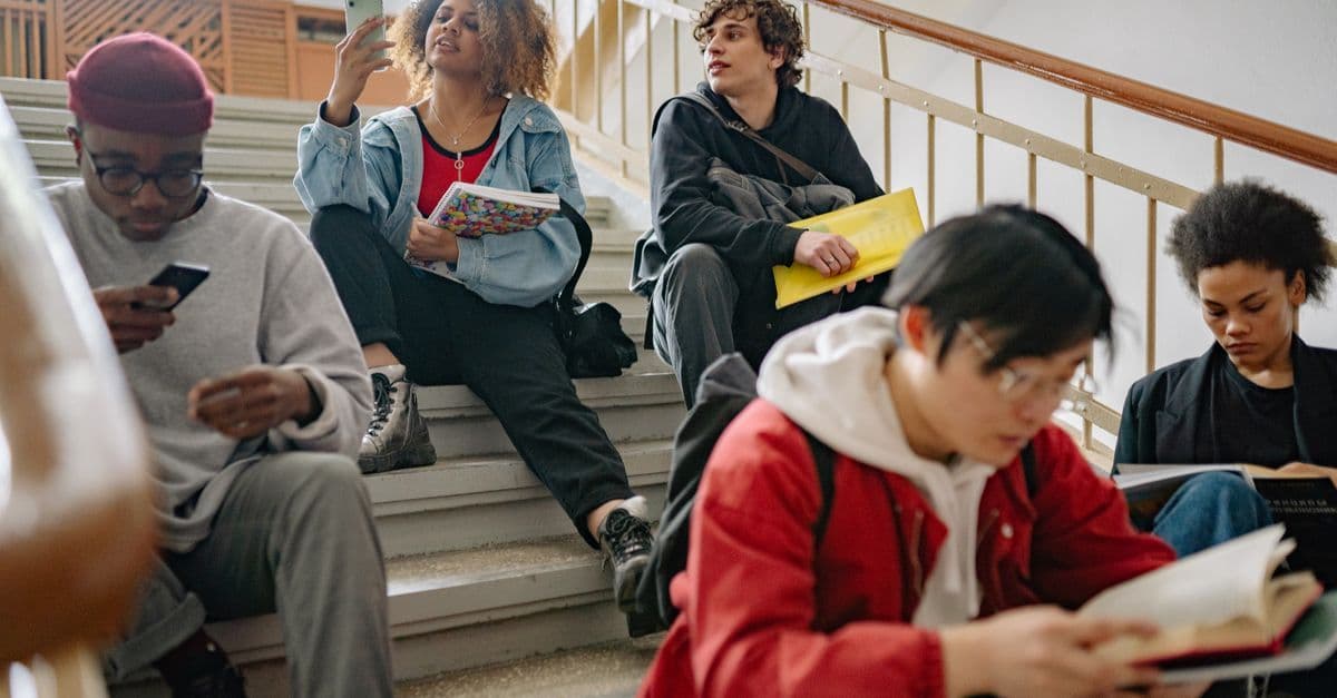 Students from various universities sitting on steps studying, reflecting International Hall's open admissions policy.