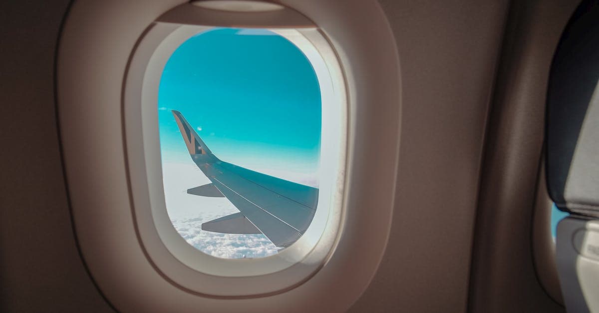 A stunning view of an airplane wing through a cabin window against a blue sky.