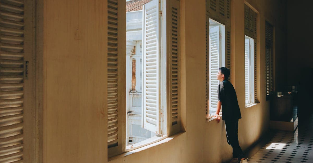 ชายมองออกไปนอกหน้าต่างบานเฟี้ยมสาดแสง สะท้อนความต้องการแพ็กเกจซิมต่างประเทศราคาคุ้มค่า