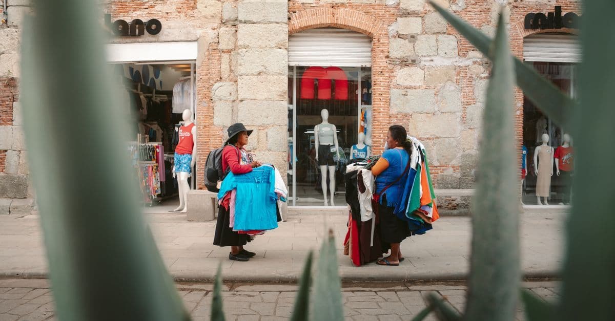 Local vendors selling traditional clothing along a colorful Oaxaca Mexico street, highlighting the city's unique cultural charm.