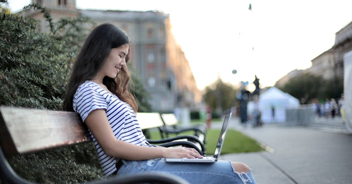 Kvinde arbejder remote på laptop i bypark og sammenligner månedlige priser på bærbar wifi