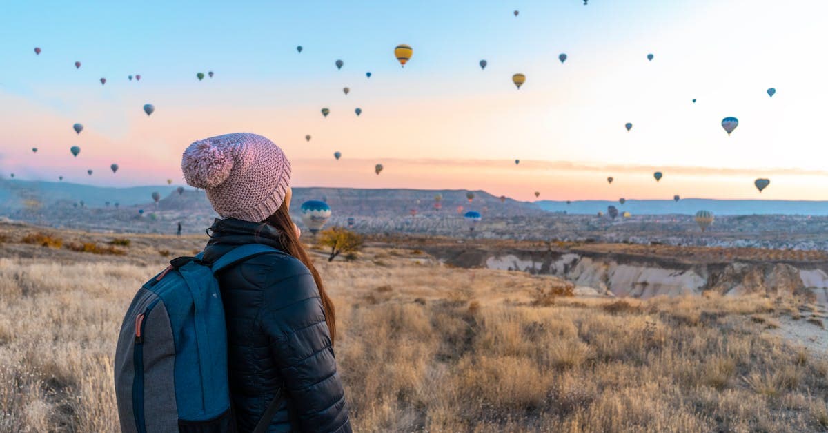 Kapadokya'da gün doğumunda renkli sıcak hava balonları izleyen gezgin, seyahat sigortasının önemini vurguluyor.