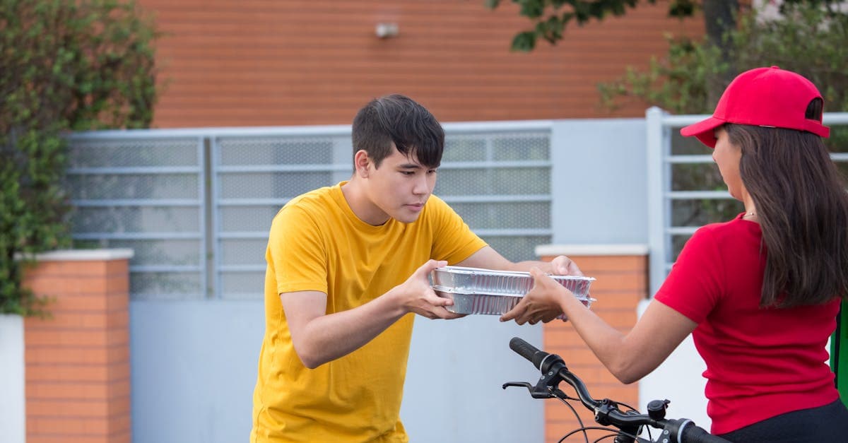 Fahrradkurier übergibt Food Meal Delivery Bestellung an Kunden vor der Haustür im direkten Dienstleister-Vergleich.