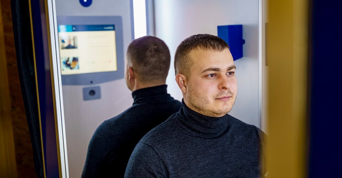 Man seated in a photobooth capturing a valid digital passport photo for an online renewal application