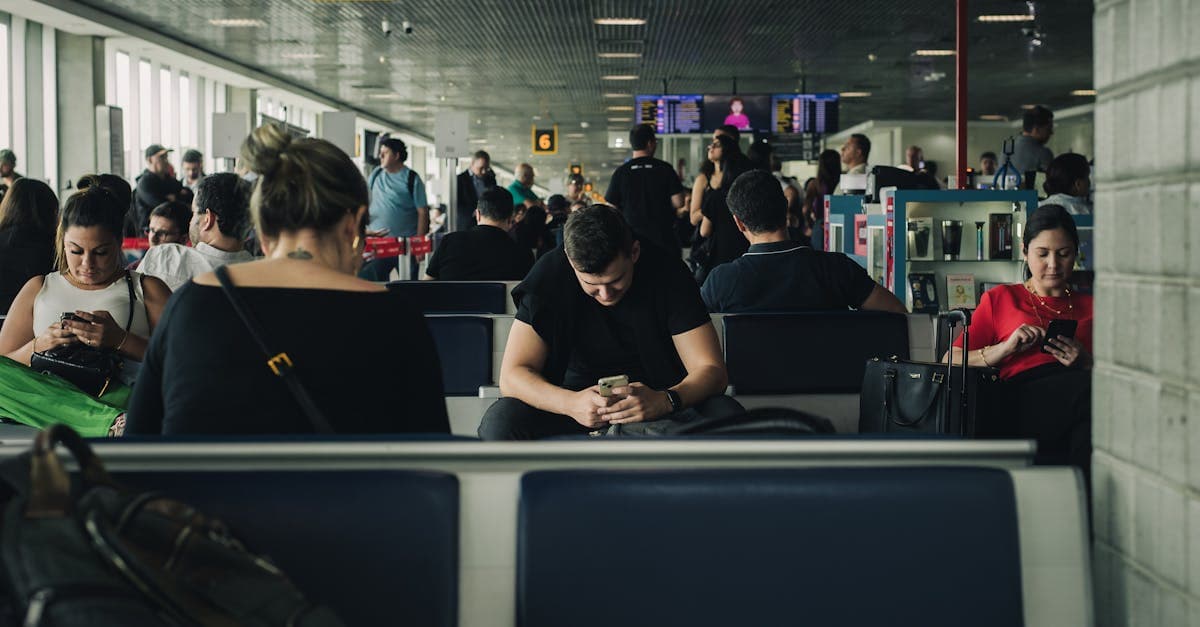 Travelers seated and waiting at São Paulo airport terminal, engaging with smartphones.