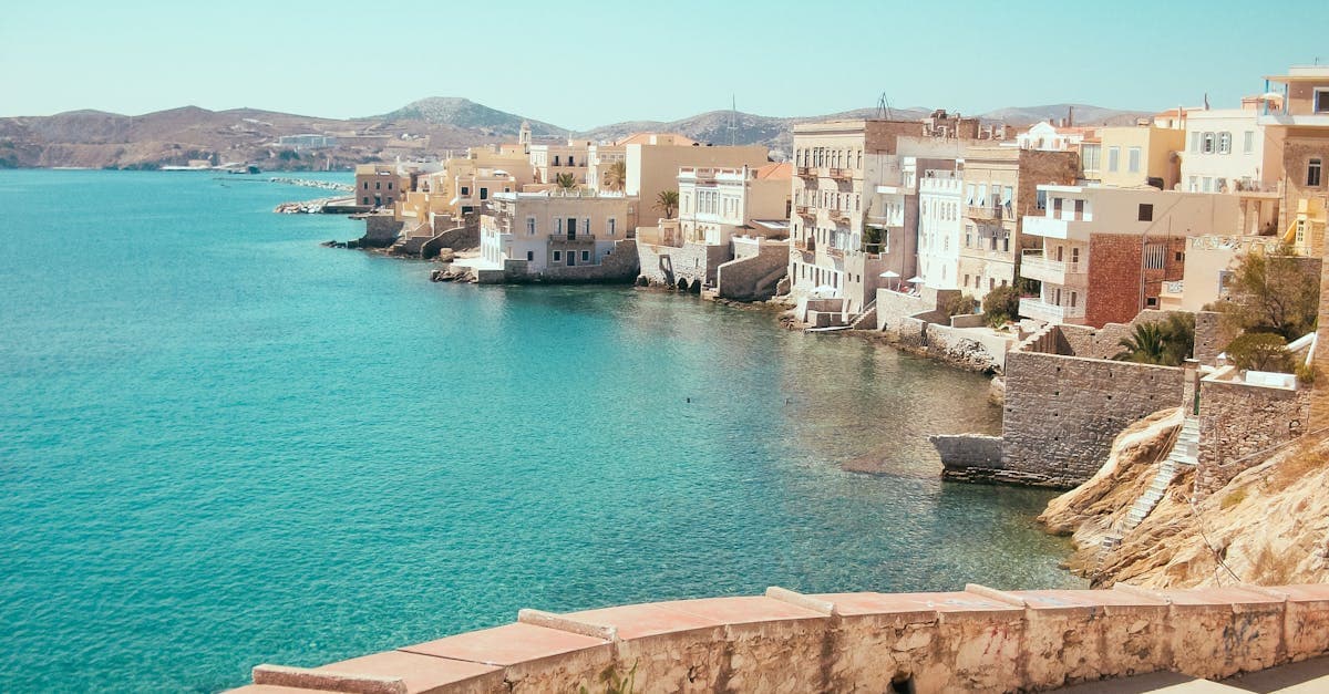 Charmig hamnstad med turkost vatten och medelhavsarkitektur – budgetvänlig resa till Grekland i solsken.