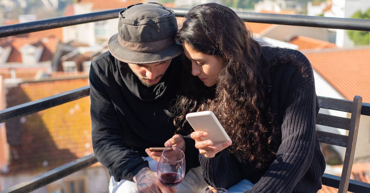 Casal desfrutando dia ensolarado com smartphones e taças de vinho em terraço em Portugal, conectados via roaming de dados