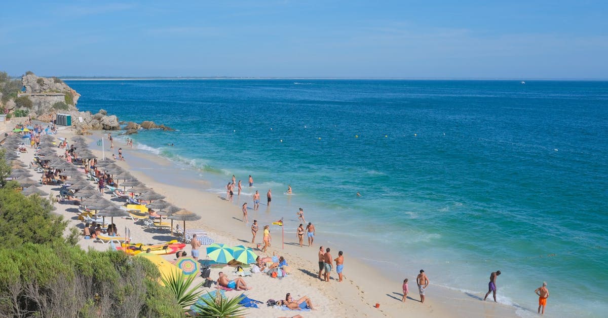 Banhistas aproveitando a praia de Portinho da Arrábida, Portugal, durante a alta temporada de verão na europa