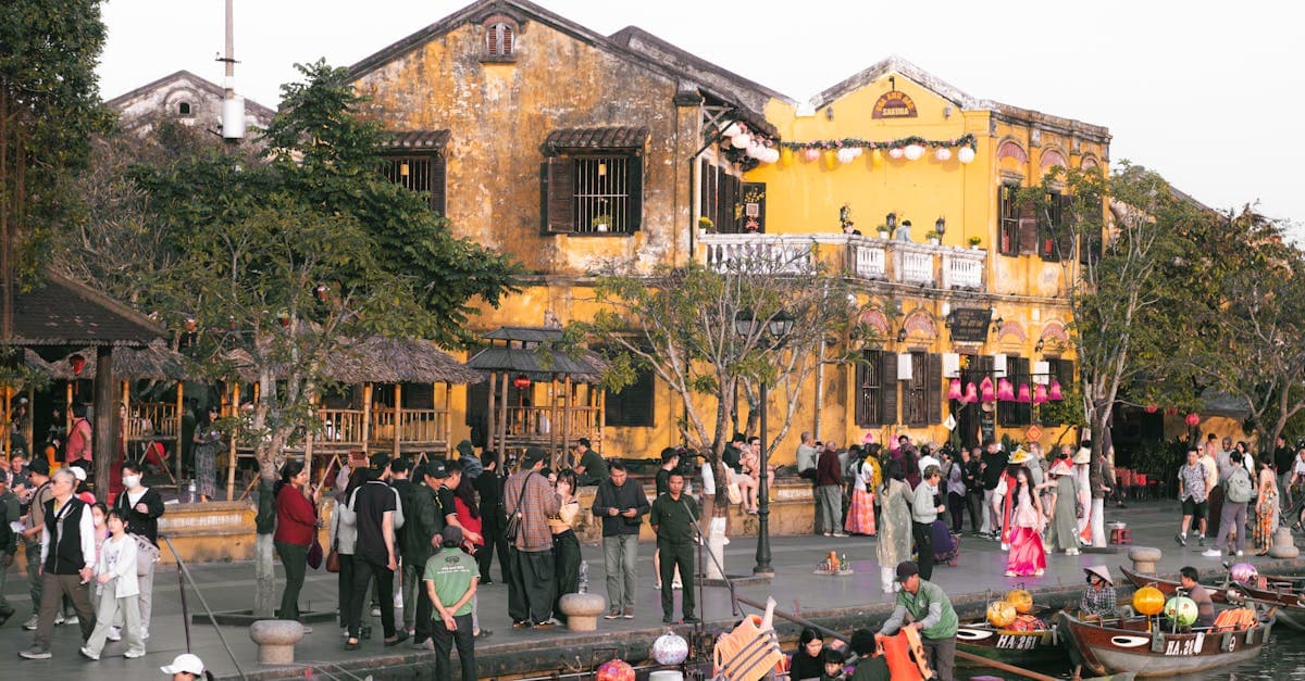 Colorful Hoi An riverside with people and traditional boats during a festival.