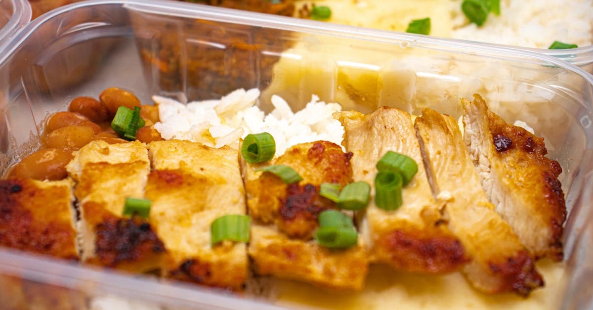 Gegrilltes Hähnchenfilet mit Frühlingszwiebeln in einer Meal-Prep-Box als gesunde und proteinreiche Mahlzeit.