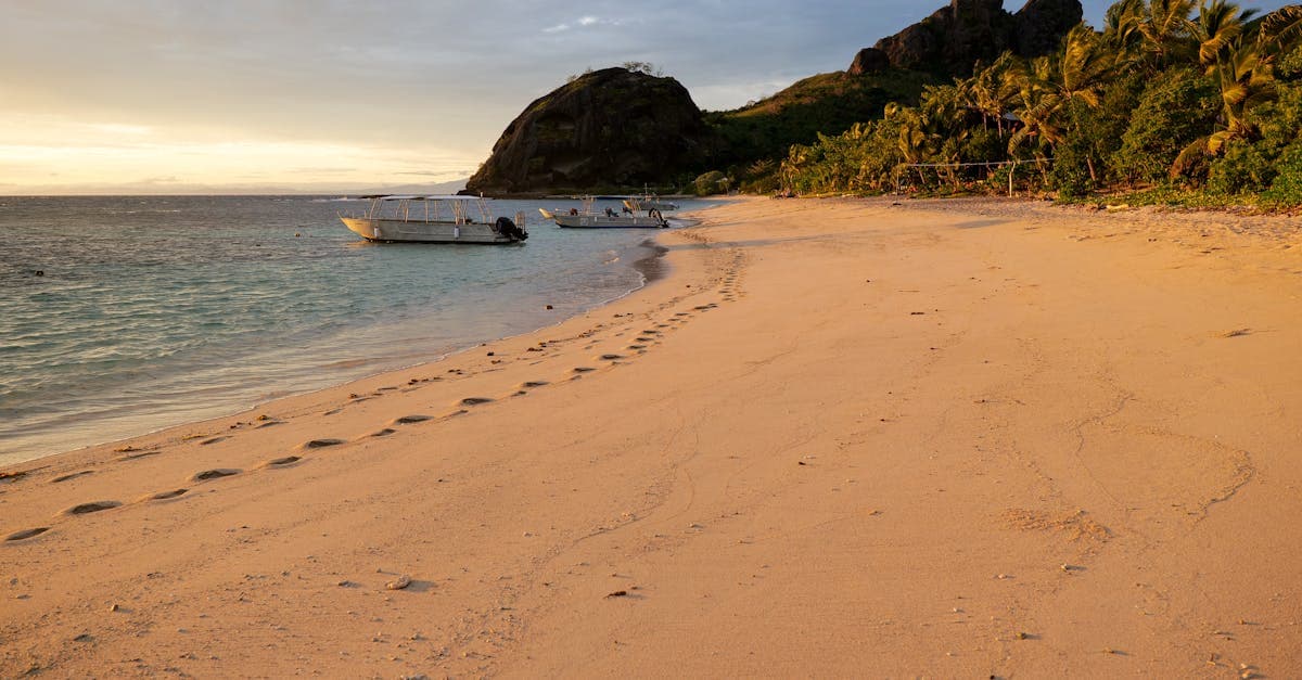 Tranquil Yasawa Islands beach at dusk with palm trees and boats, a top Fiji destination for Australians