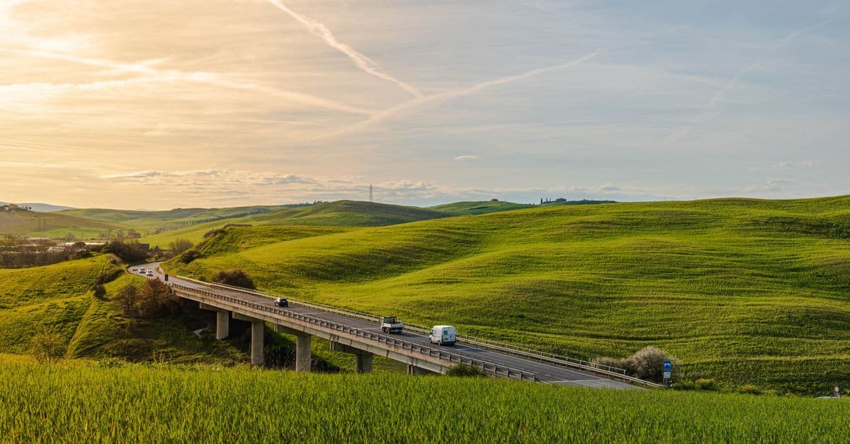 Autostrada panoramica che attraversa le colline toscane al tramonto, simbolo del road trip per eccellenza.