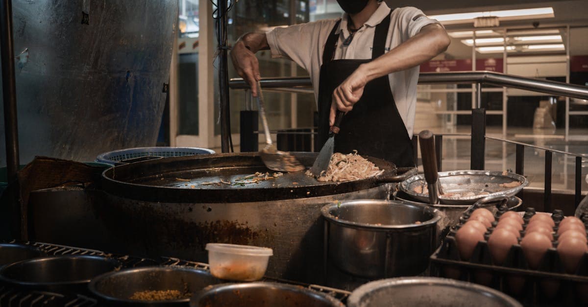 Chef skilfully preparing traditional Thai regional dishes featuring key ingredients at Bangkok market stall.