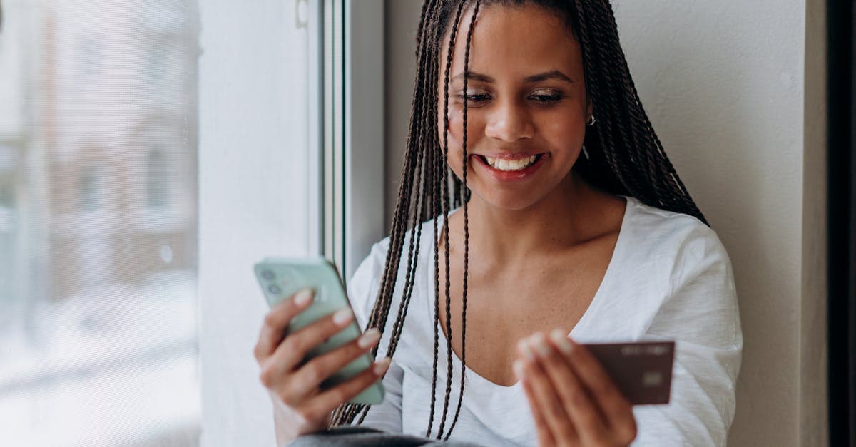 Mujer sonriente comprobando que creditea es confiable con su smartphone y tarjeta de crédito en casa