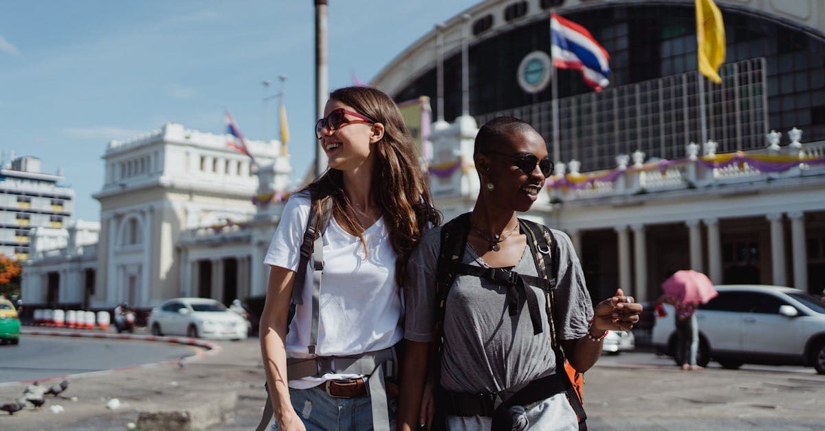 Two women smiling outside a Bangkok railway station, discovering why Thailand tops the 2026 travel bucket list