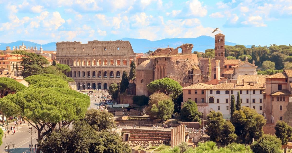 Vista aérea do Coliseu e do centro histórico de Roma sob um céu azul vibrante