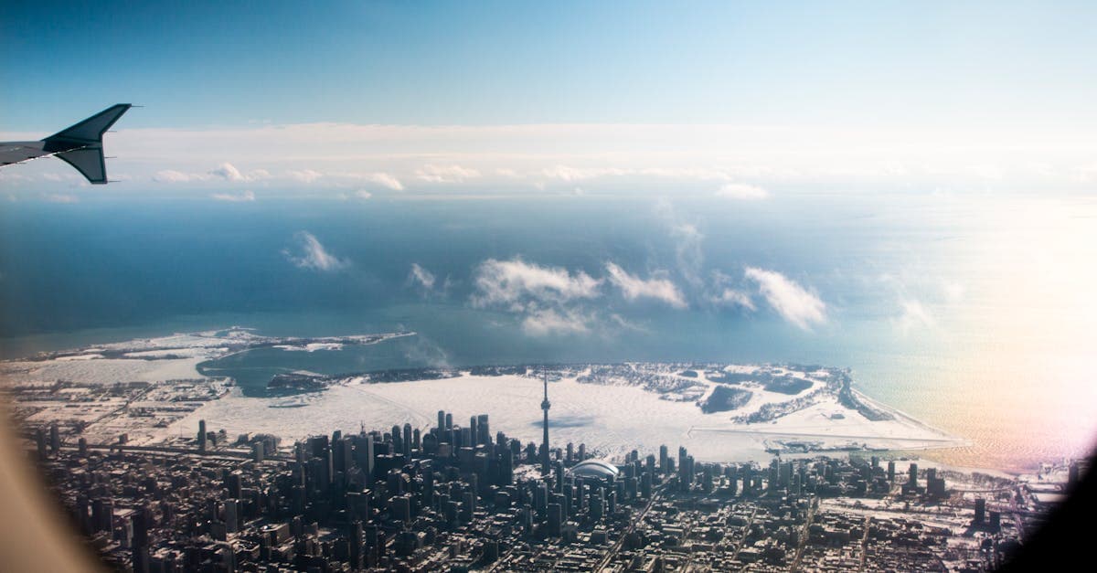Aerial winter view of Toronto's snowy CN Tower skyline photographed from a plane window heading to Delhi