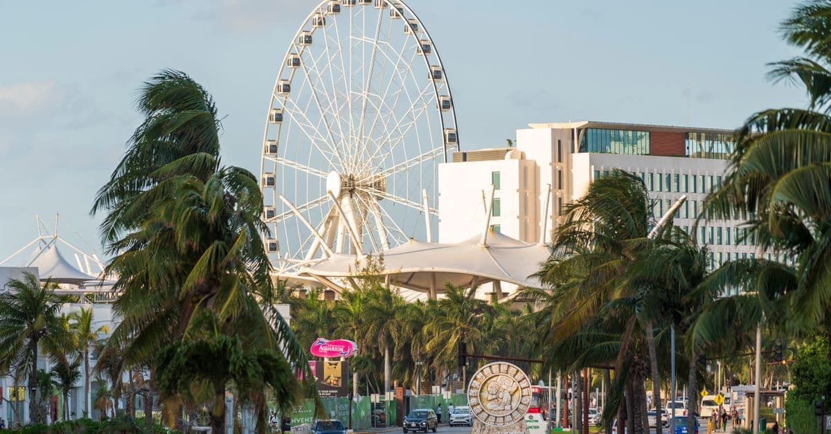 Cancun cityscape with ferris wheel and palm trees, where staying connected with a travel eSIM is essential