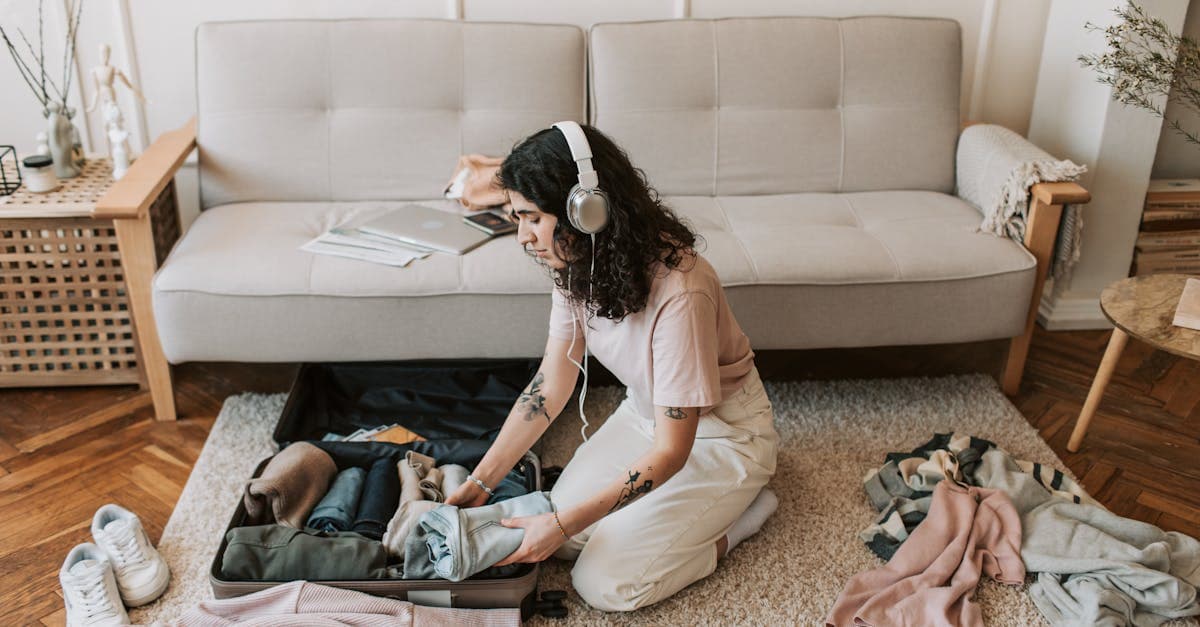 Woman wearing headphones packs a suitcase on the floor, using the ultimate travel checklist for any trip.