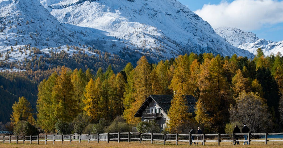 Scenic autumn view in Sils im Engadin with snowy mountains and a cozy cabin.