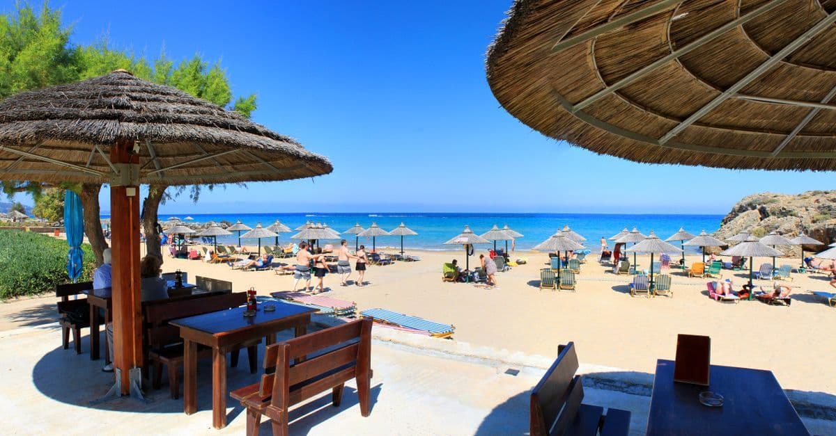 Sonnenschirme und klares Wasser an einem Kreta-Strand im Oktober zeigen das angenehme Wetter Kreta im Herbst.