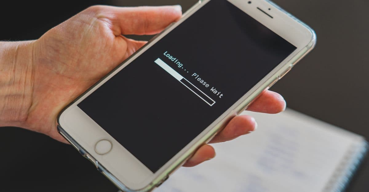 Hand som håller en iPhone med laddningsskärm för att aktivera wifi hotspot under resan.
