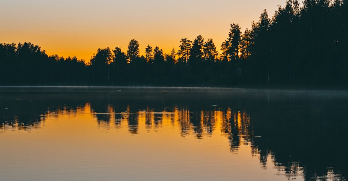 Auringonnousu heijastuu tyyneen järveen Jyväskylässä – jatkuva matkavakuutus sopii paljon matkustaville henkilöille.