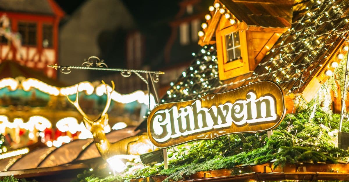 イルミネーションに彩られた屋台に「Glühwein」の看板が掲げられ、クリスマスマーケットの温かな雰囲気が漂う。