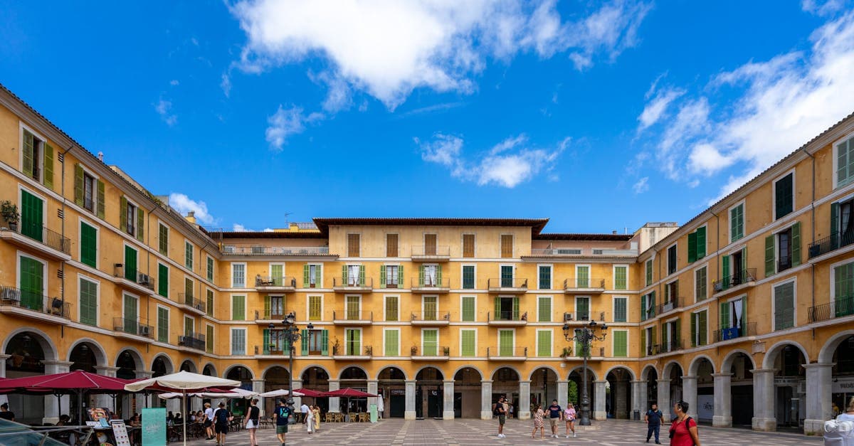 Zonnig Plaza Mayor in Palma de Mallorca met terrassen en historische gevels bij warm weer Mallorca.