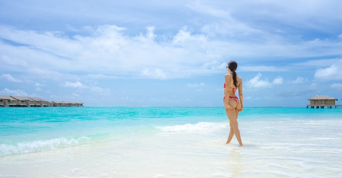 Donna in bikini su una spiaggia tropicale con acque cristalline e cielo soleggiato delle Maldive