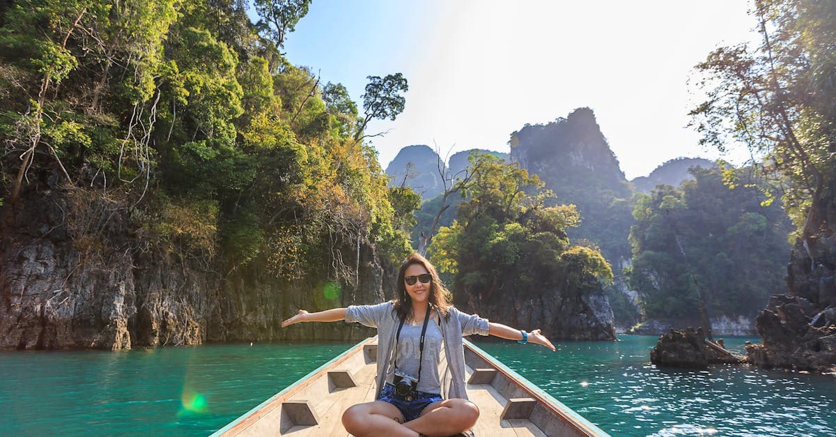 Vrouw geniet van een boottocht door het karstlandschap van Thailand, passend bij veelgestelde vragen over reisadvies thailand.