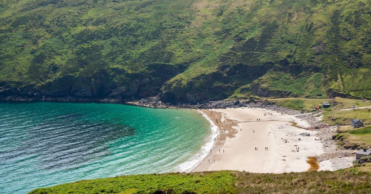 Serene Irish beach with turquoise water and green hills on a calm summer day