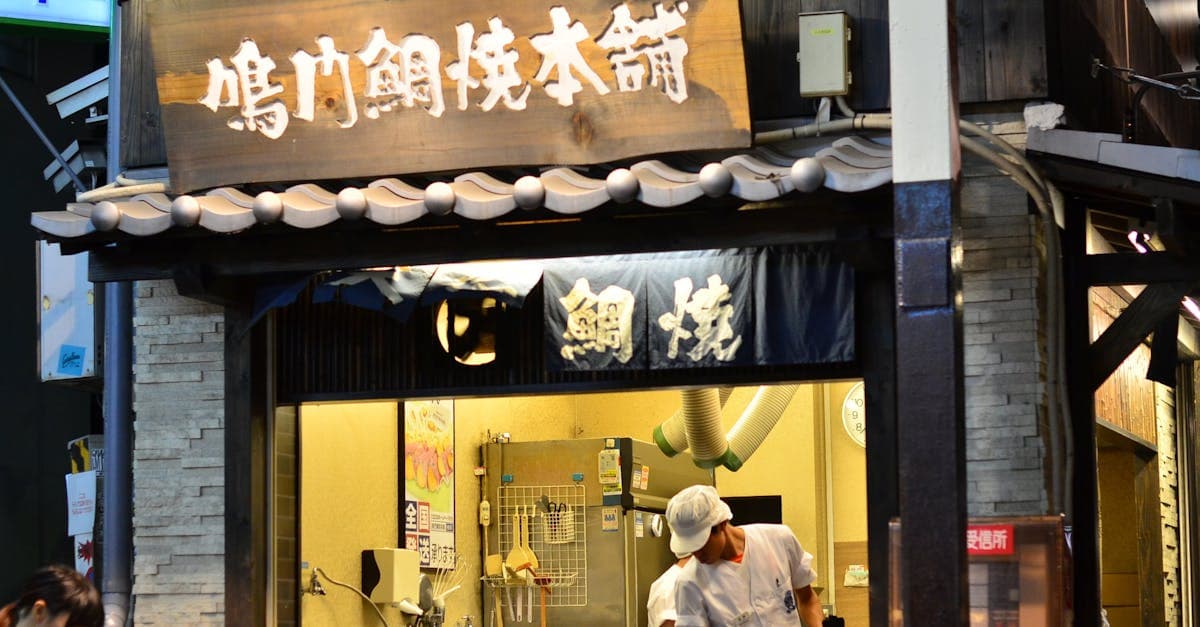 大阪の伝統的な屋台で料理を準備する店主、ソウル フードと呼ばれる由来を体現する日本の食の現場