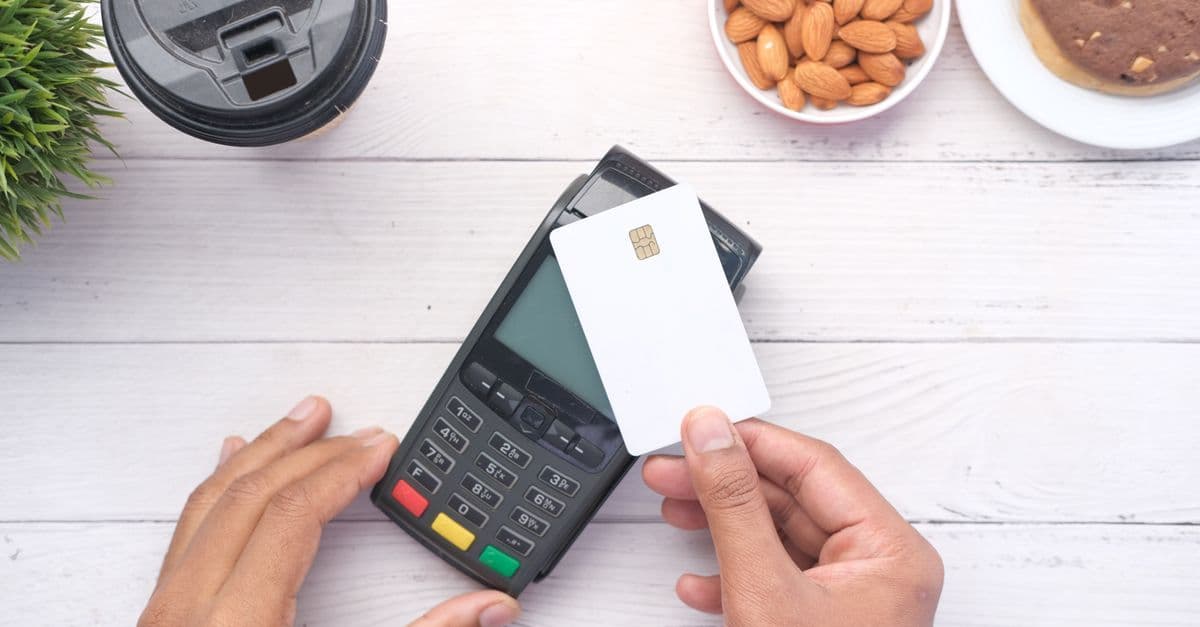 Contactless card payment on a wooden table, representing Tesco pay as you go SIM bundle costs.