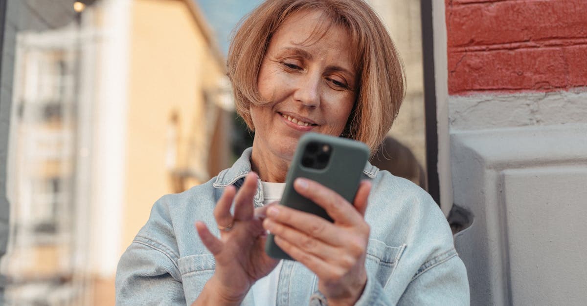 Woman in a denim jacket smiling at her smartphone outdoors, weighing travel eSIM against carrier international roaming plans