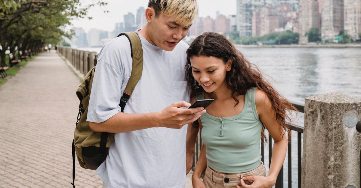 Young couple smiling and browsing photos on a smartphone while staying connected after arriving in the United States.