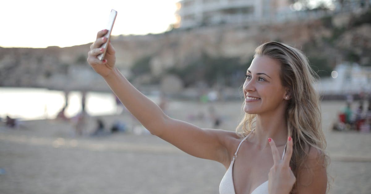 Young woman taking a beach selfie in Ibiza, enjoying reliable mobile data without expensive roaming charges