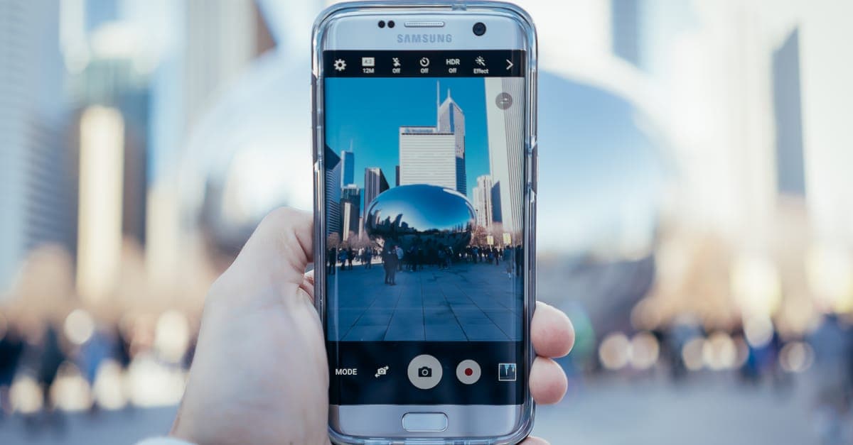 Hand hält Smartphone vor städtischer Spiegelung – so greifst du unterwegs auf Samsung Cloud zu.