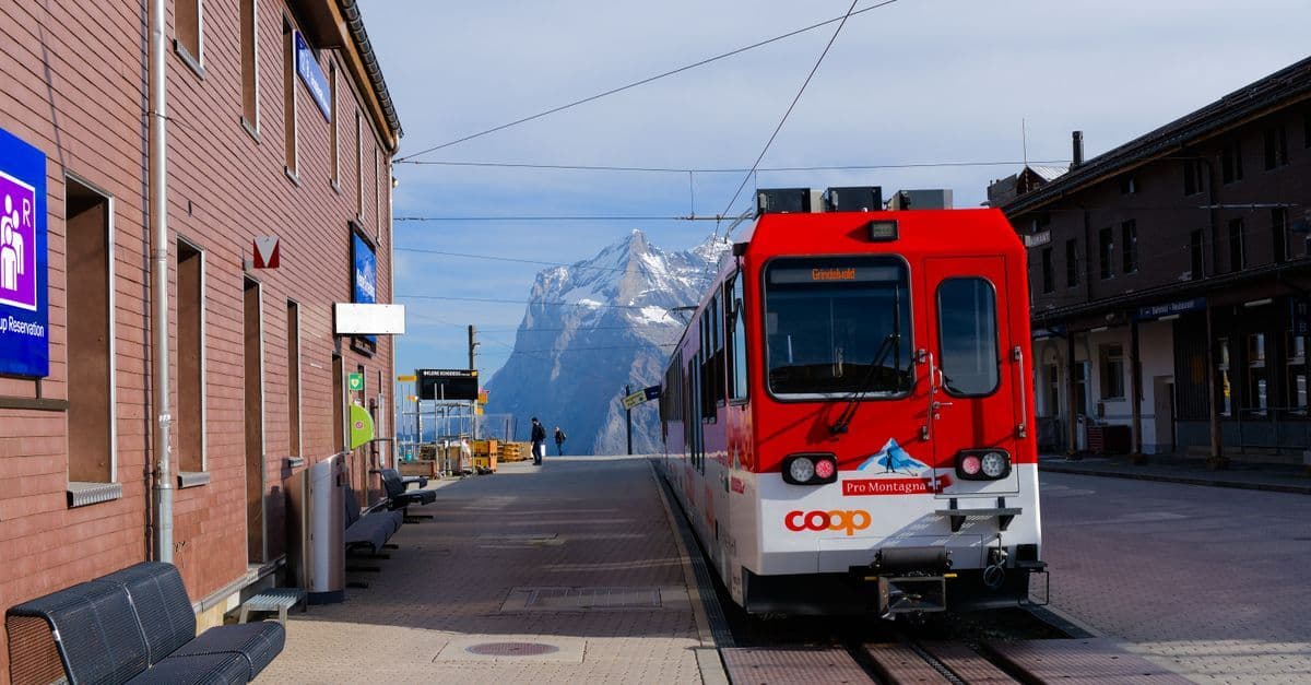 Roter Schweizer Zug an einem Bergbahnhof – Coop Travel bietet unvergessliche Reiseerlebnisse in der Schweiz