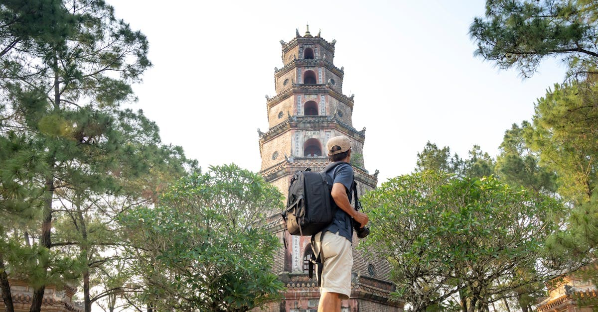 Solo traveller gazing at an ancient Vietnamese pagoda from a scenic viewpoint while backpacking Southeast Asia