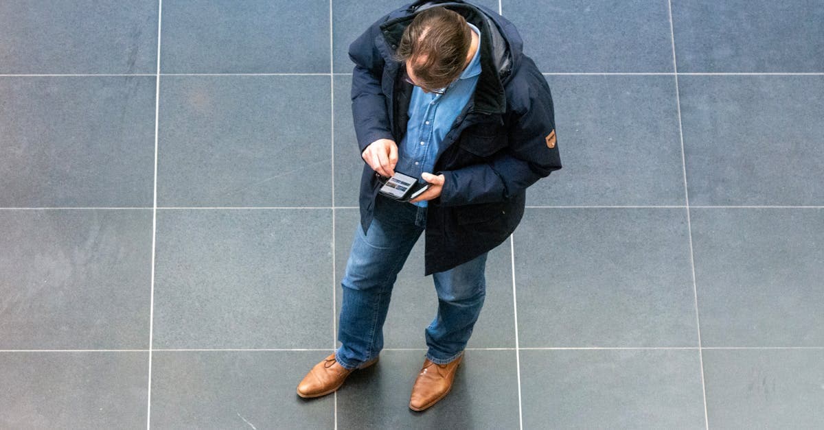 室内でスマートフォンを見つめる男性の俯瞰写真。dアカウントIDを忘れた場合の確認方法と状況別対処法を調べる場面。